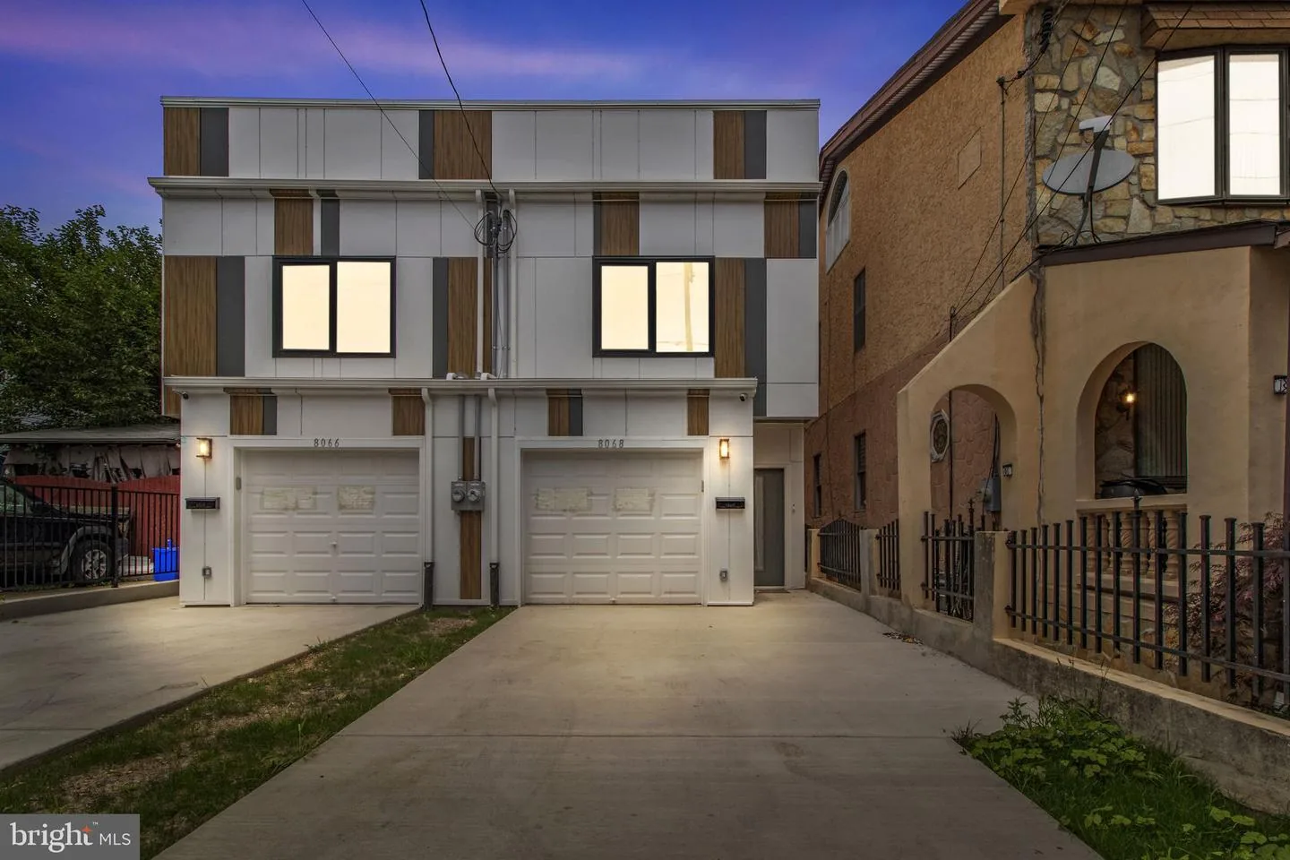 Two twin homes with garages on Craig Street at dusk